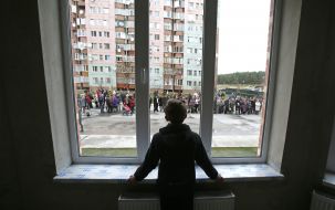 Мальчик смотрит из окна здания 