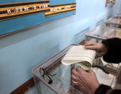 The woman puts the ballot in the ballot box