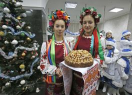 Девушки в украинских национальных костюмах держат каравай