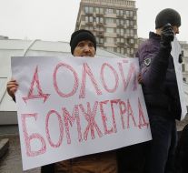 An elderly woman holds a placard