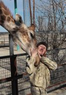 Сотрудница парке возле жирафа