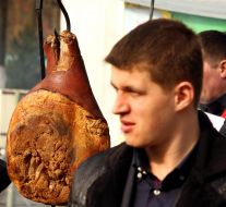 Посетители проходят возле копченого мяса