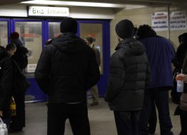 Люди стоять перед закритим входом на станцію метро