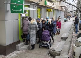 Люди стоять у черзі до банкомату