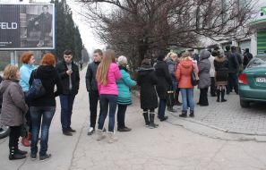 Люди стоять у черзі до банкомату