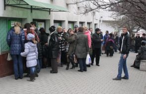 Люди стоять у черзі до банкомату