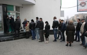 Люди стоять у черзі до банкомату