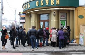 Люди стоять у черзі до банкомату