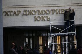 Workers take off a signboard from building of Crimea parliament 