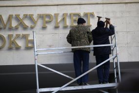 Workers take off a signboard from building of Crimea parliament 