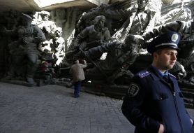 Чоловік покладає квіти до скульптурної композиції