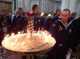 A sailor puts a candle 