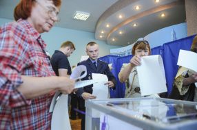 Electors put a bulletin into an urn for voting