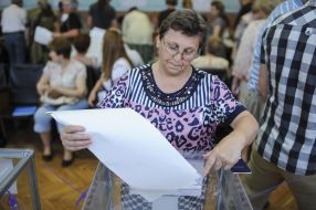 Electors put a bulletin into an urn for voting