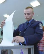 Electors put a bulletin into an urn for voting