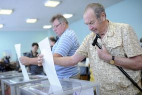 Electors put a bulletin into an urn for voting