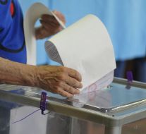 A woman gives up a bulletin in an urn for voting