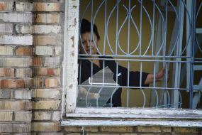 Woman looks out the broken window