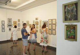 Visitors look at paintings in the exhibition "Flash"
