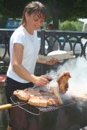 The woman prepares the meat on the grill