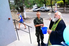 A priest blesses a house