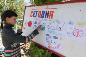 A girl stands near the stand with pictures
