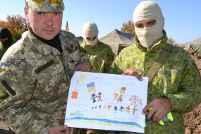 Military personnel hold children's drawings