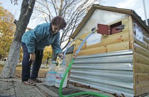 A woman collects water in plastic containers