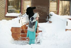 Люди убирают снег возле здания