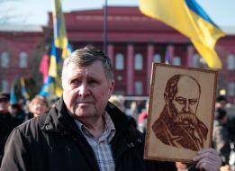 A man holds a portrait of Taras Shevchenko