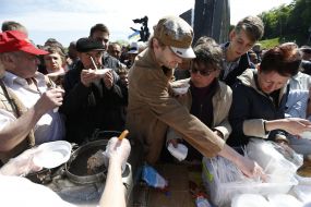 Участники праздничного митинга стоят в очереди за кашей