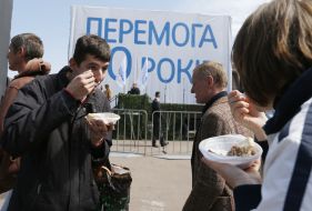 Участники праздничного митинга едят гречневую кашу