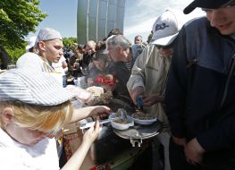 Участники праздничного митинга стоят в очереди за кашей