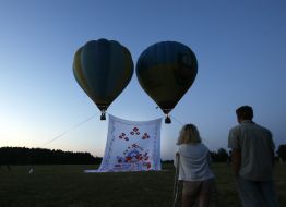 Balloons rise giant towel in the sky