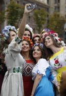 Дівчата в українських віночках фотографуються на телефон