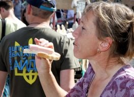 Женщина ест бутерброд с колбасой