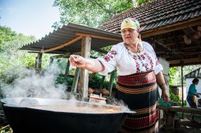 A woman prepares a huge pot of borscht