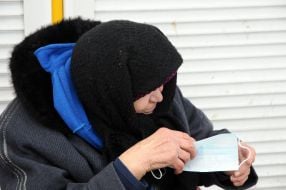 An elderly woman examines mask