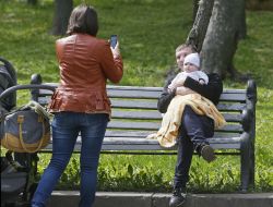 A woman photographs the man with the child