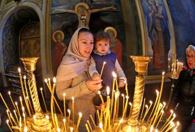 A woman with a baby puts a candle
