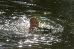 A man with a wreath of wild flowers in water