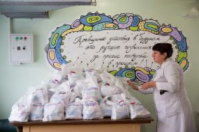 Worker of charity canteen puts kits