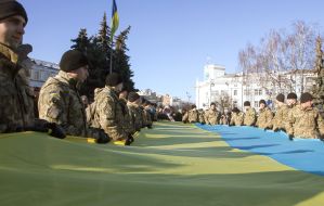 Soldiers carry a huge flag of Ukraine