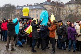 Люди запускают в небо желтые и синие небесные фонарики