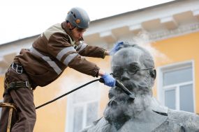Worker cleaning company washes monument to Mikhail Grushevsky