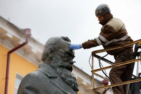 Worker cleaning company washes monument to Mikhail Grushevsky