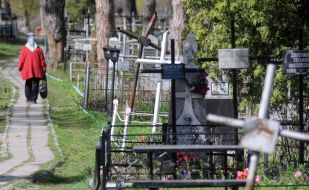 An elderly woman walks past graves