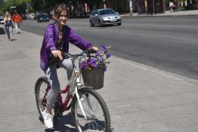 Girl on a bicycle with a bouquet in a bucket