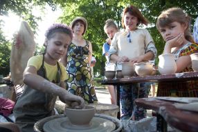 The girl makes dishes from clay on a potter's wheel
