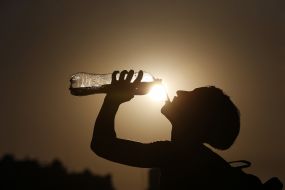The girl drinks water from the bottle